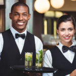 two hospitality workers with trays and drinks | What is Your Hospitality Background Check Missing | Barada Associates